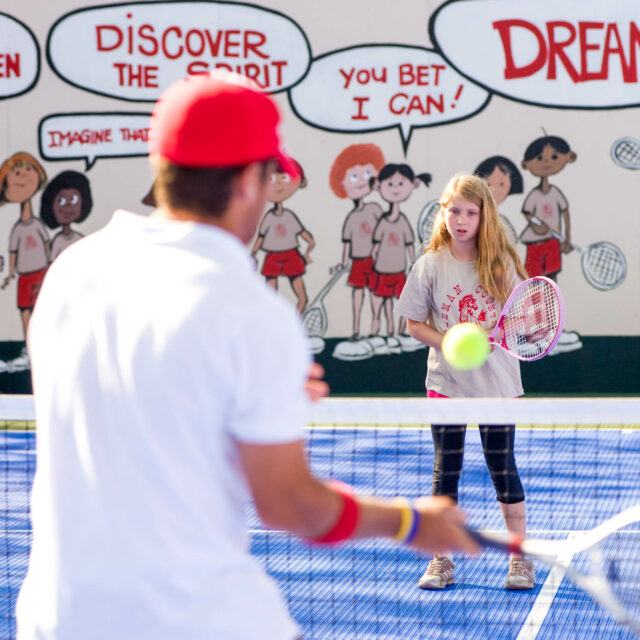 Camper playing tennis with an adult.