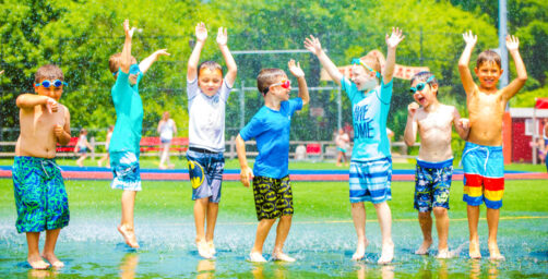 Campers jump around in water spray