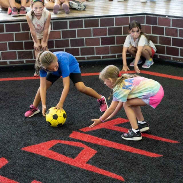 Two girl campers playing Gaga in the pit together