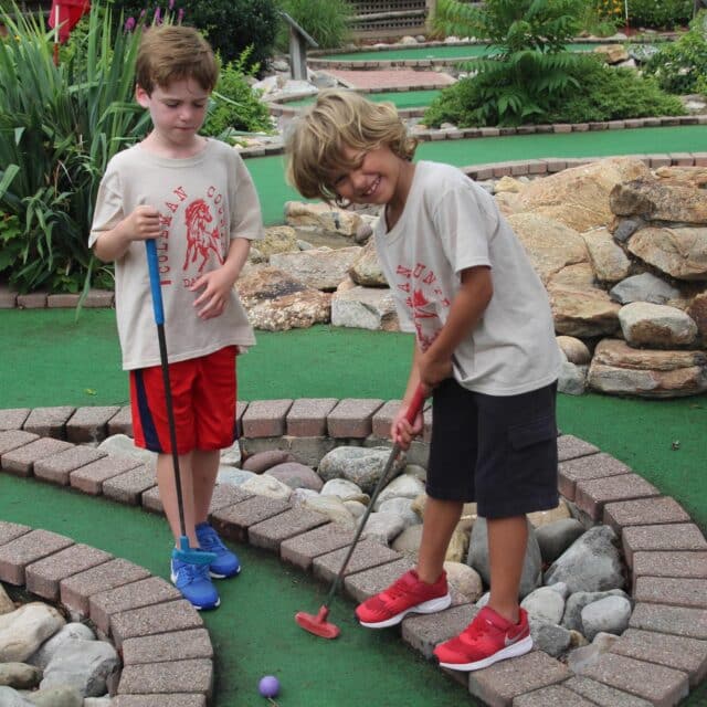 Two boy campers playing mini golf