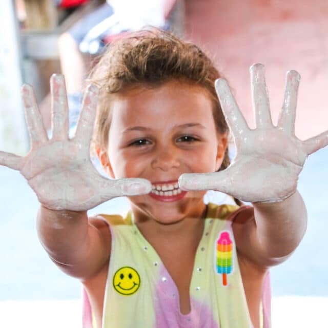 Scout camper with clay on her hands.