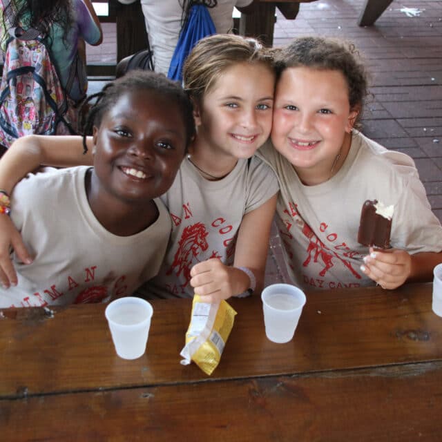 Three girl campers having a snack together