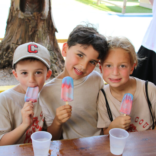 Three campers eating popsicles together