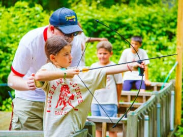 Instructor helps camper with archery