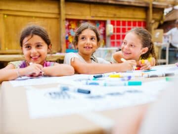 Three girls draw at camp