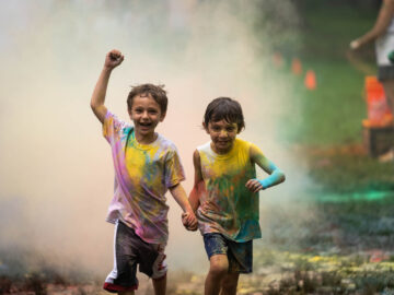 Two boys running together in the color run.