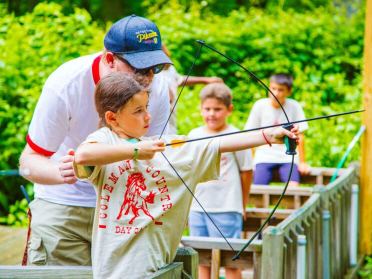 Camper doing archery with the help of a counselor.