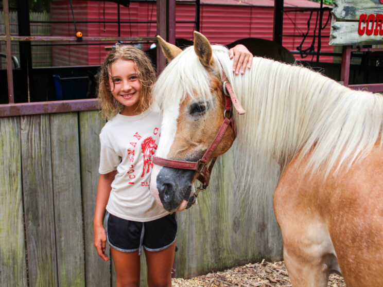 Camper with her arm around a horse.