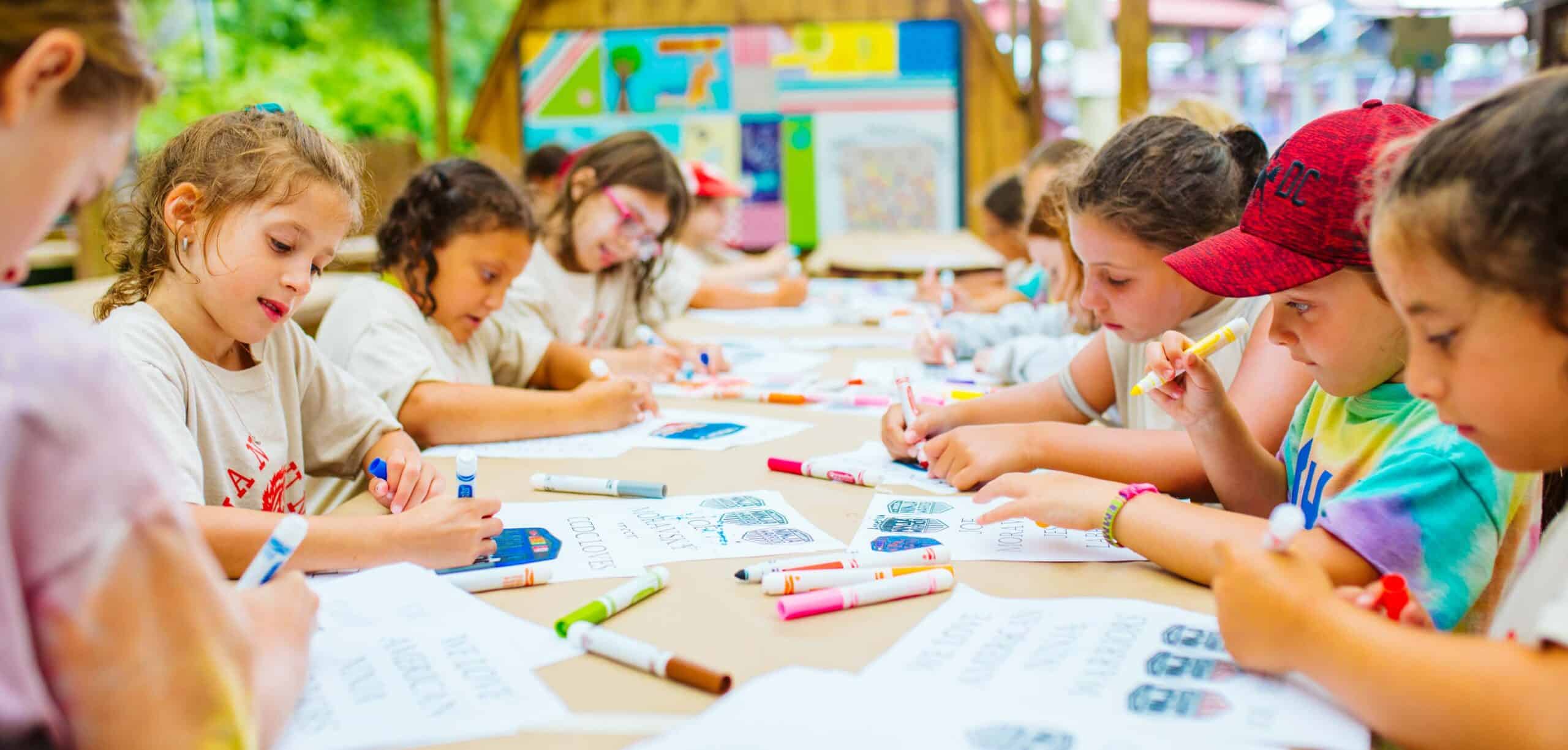 Group of campers color at long table