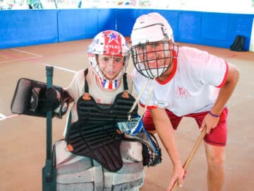 Camper playing indoor hockey with a counselor.