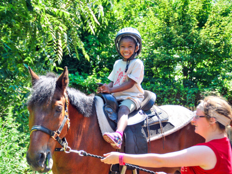 Camper smiling while riding a horse.