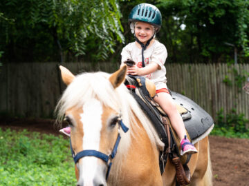 Camper smiling while sitting atop a horse.