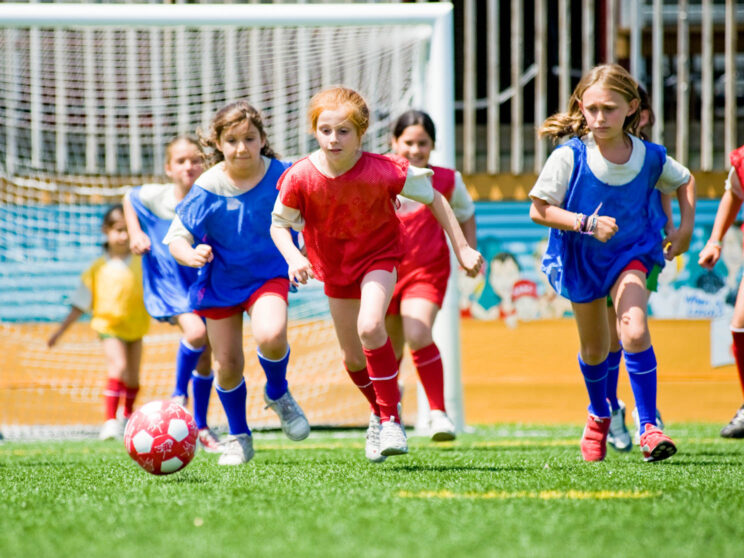 Campers run toward ball during soccer game