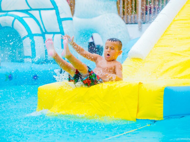 Young camper makes a splash at the end of a water slide