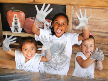 Campers hold up hands covered in clay