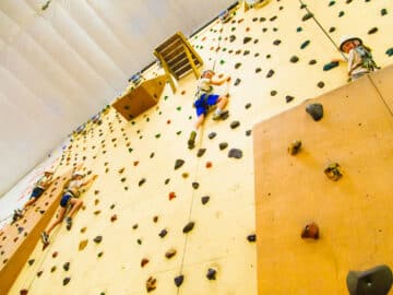 Campers climb indoor rock wall