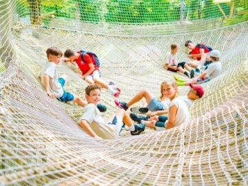 Group of campers lounge in challenge course net