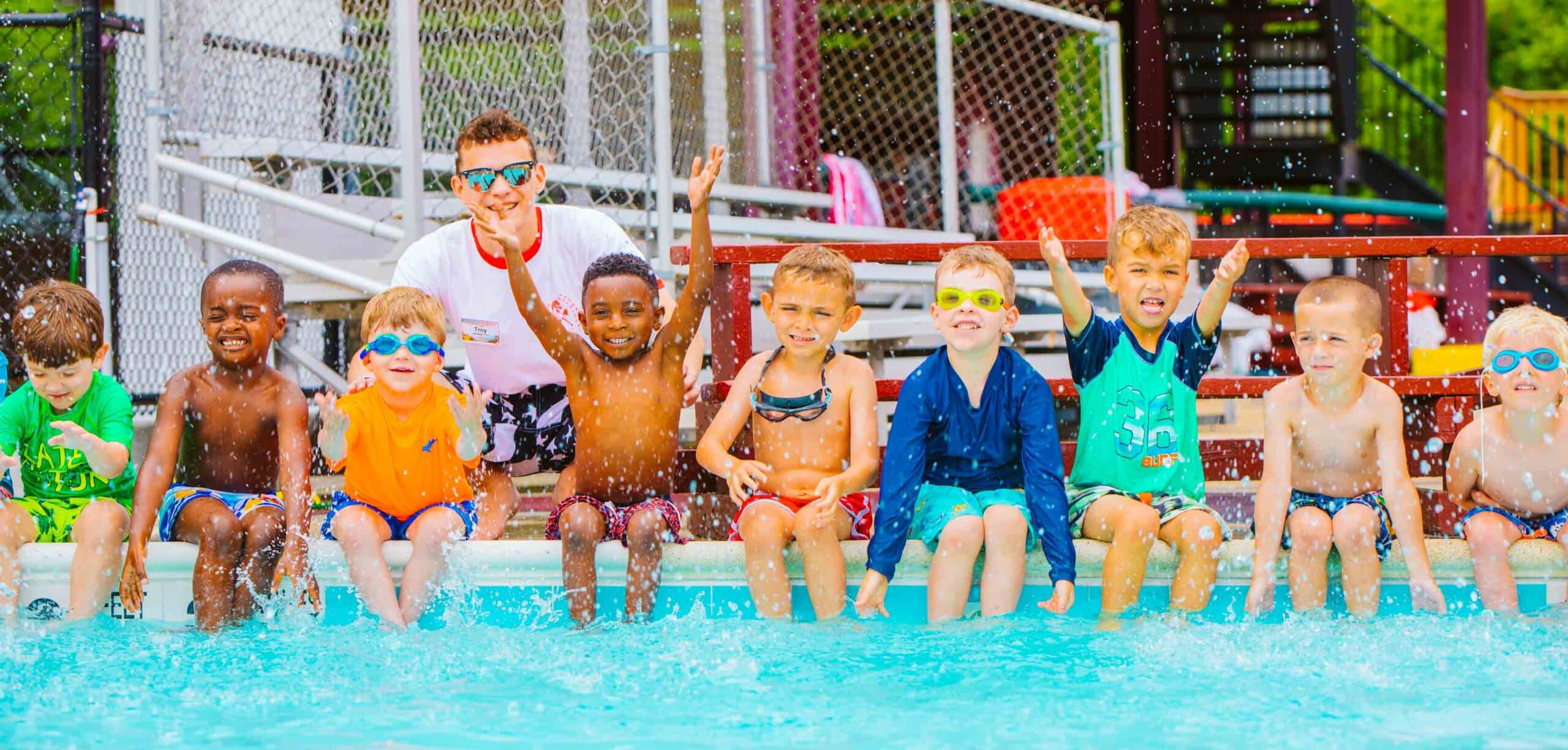 Line of campers splash from edge of pool