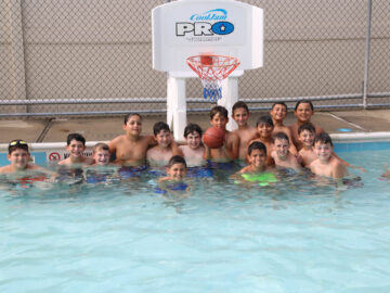 Boy campers playing basketball in the pool.