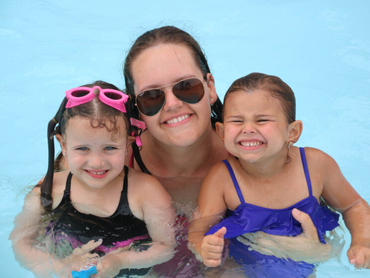 Counselor with two young campers in the pool.