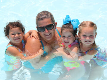 Counselor with three young campers in the pool.