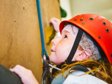 Close up of young girl climbing rock wall