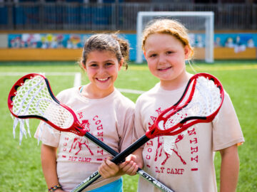 Two girls hold crossed lacrosse sticks