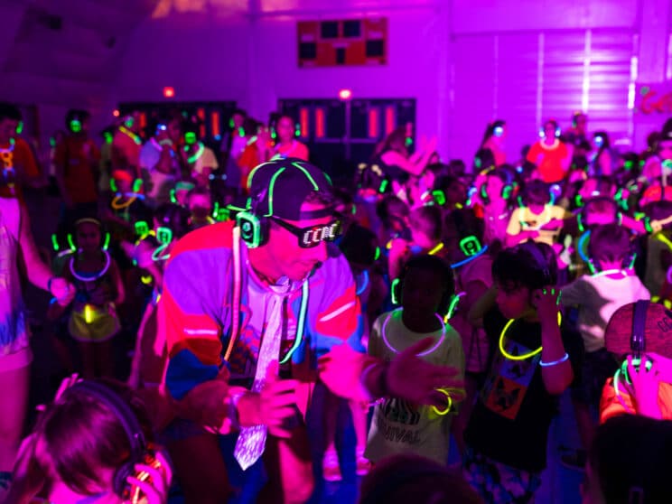 Campers and counselors dancing in the dome with purple lights and glow necklaces