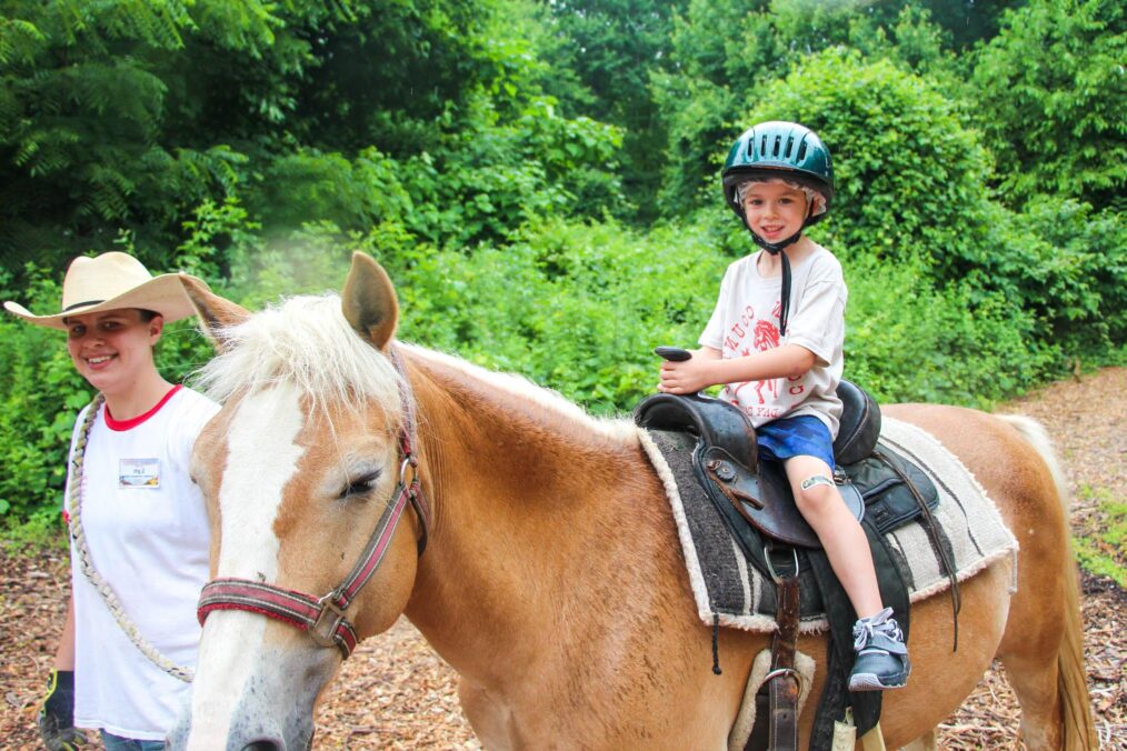 Young boy riding a horse on a trail