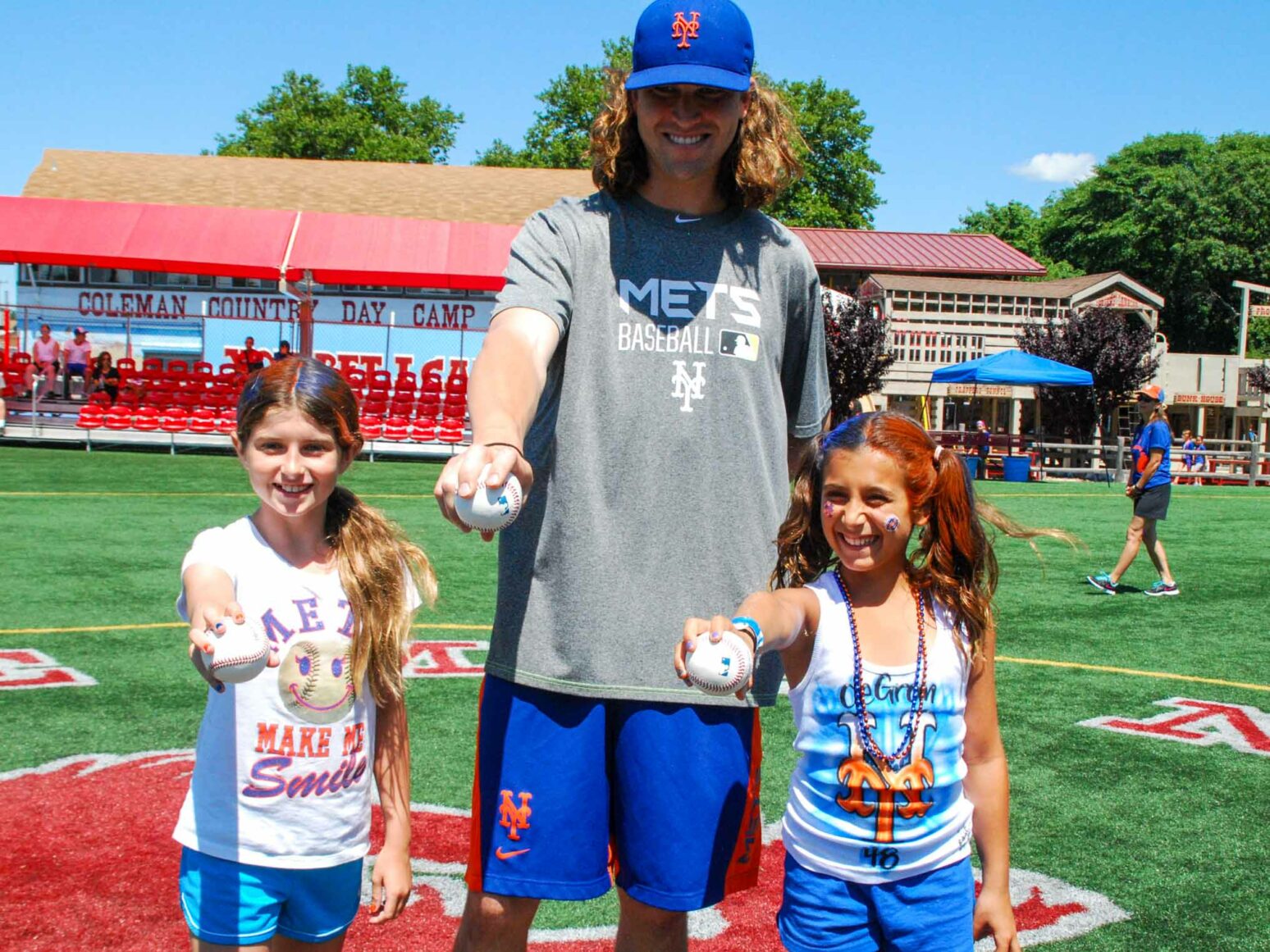 Two young campers hold out baseballs with Jacob deGrom