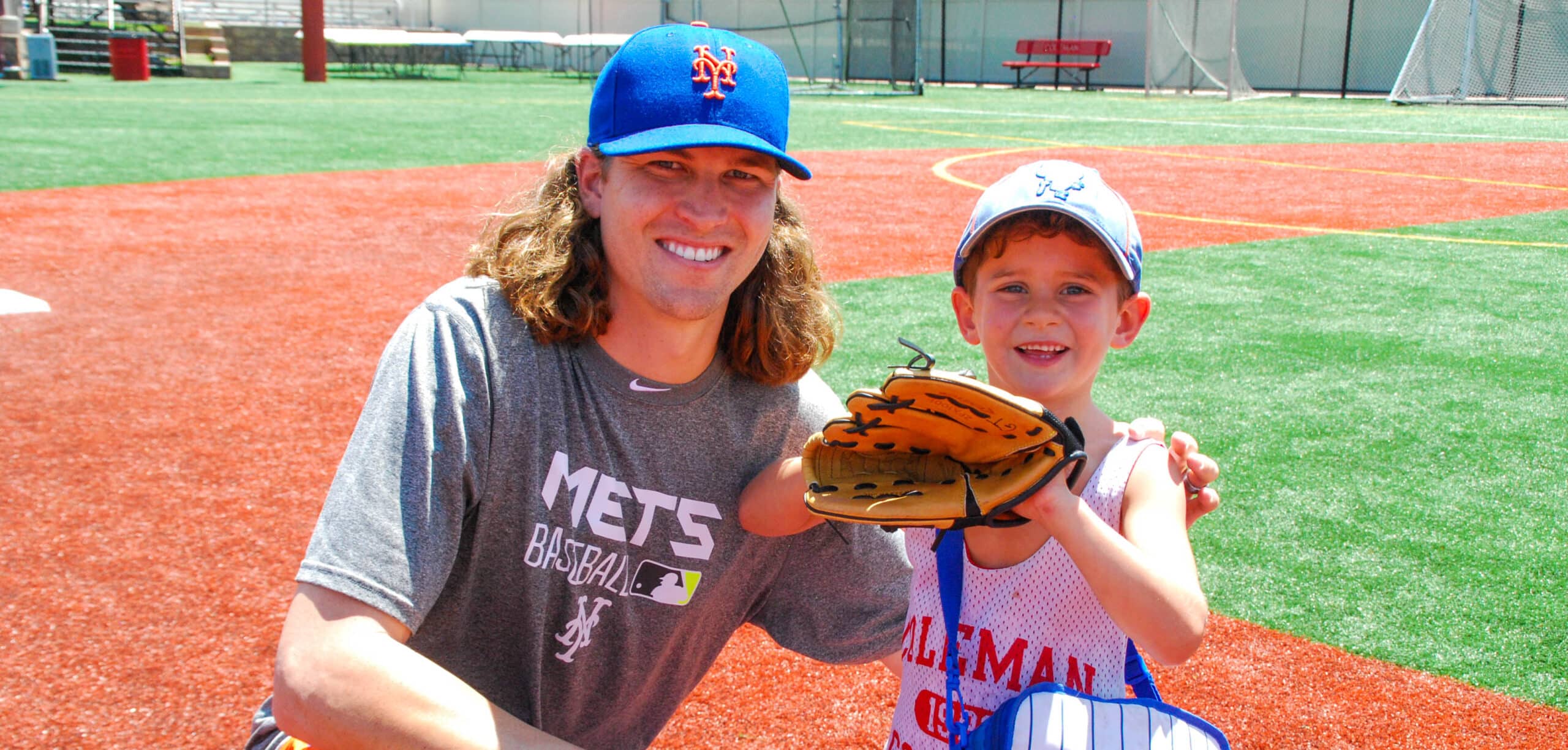 Mets player taking a picture of a camper on the baseball field.