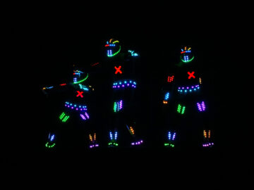 Three people appear as neon lights in the dark