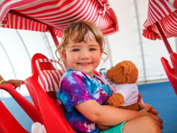 PIT camper smiling with a teddy bear.