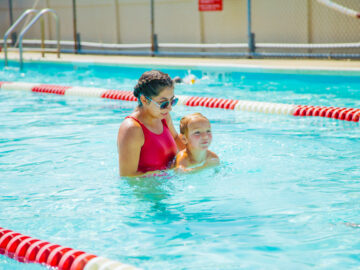 Swim teacher supporting a young camper in the pool as she swims