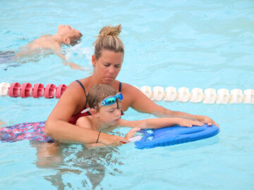 Counselor teaching a camper to swim.