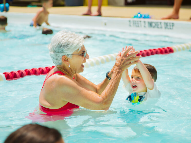 Older swim teacher helping a young camper learn to swim