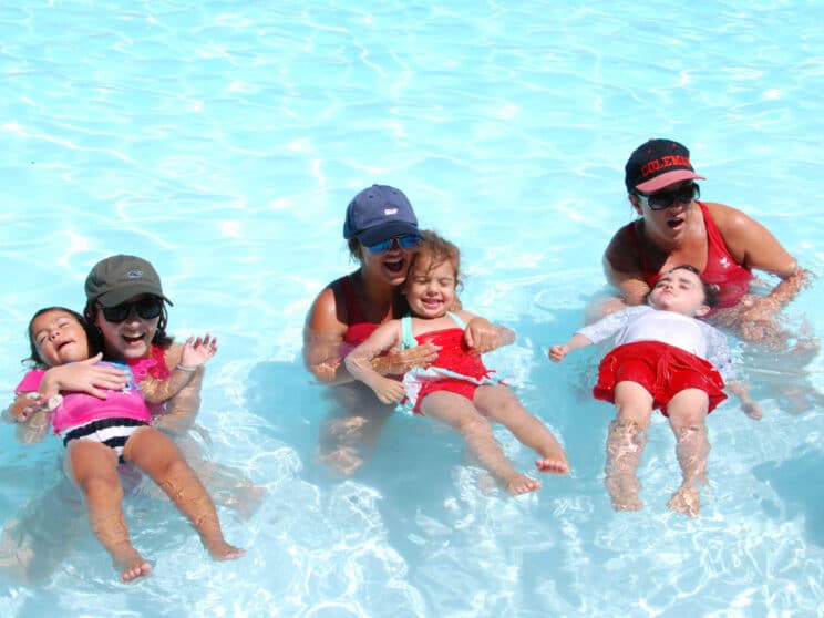 Three counselors each with a camper teaching them how to swim.