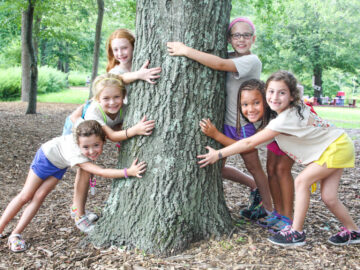 Group of campers hugging a tree.
