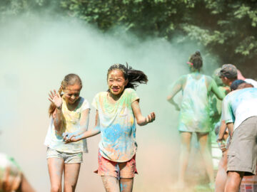 Two girl campers running and getting color thrown on them