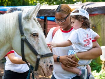 Young camper petting a horse.