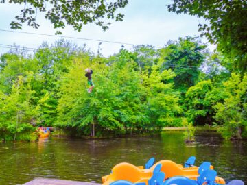 Camper ziplines over pond