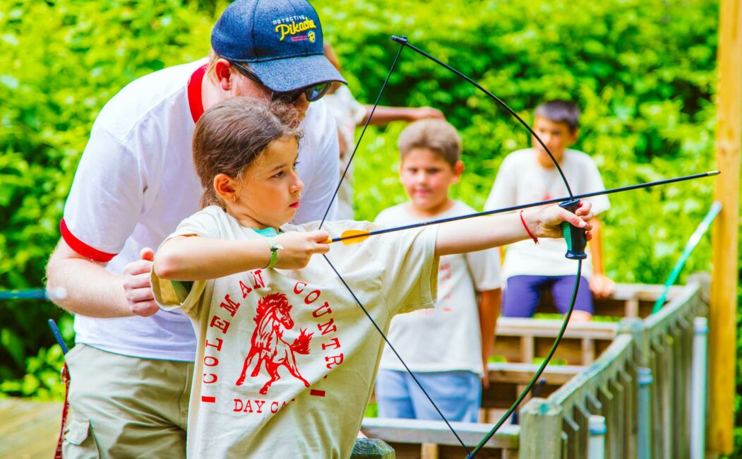 Instructor helps campers with archery