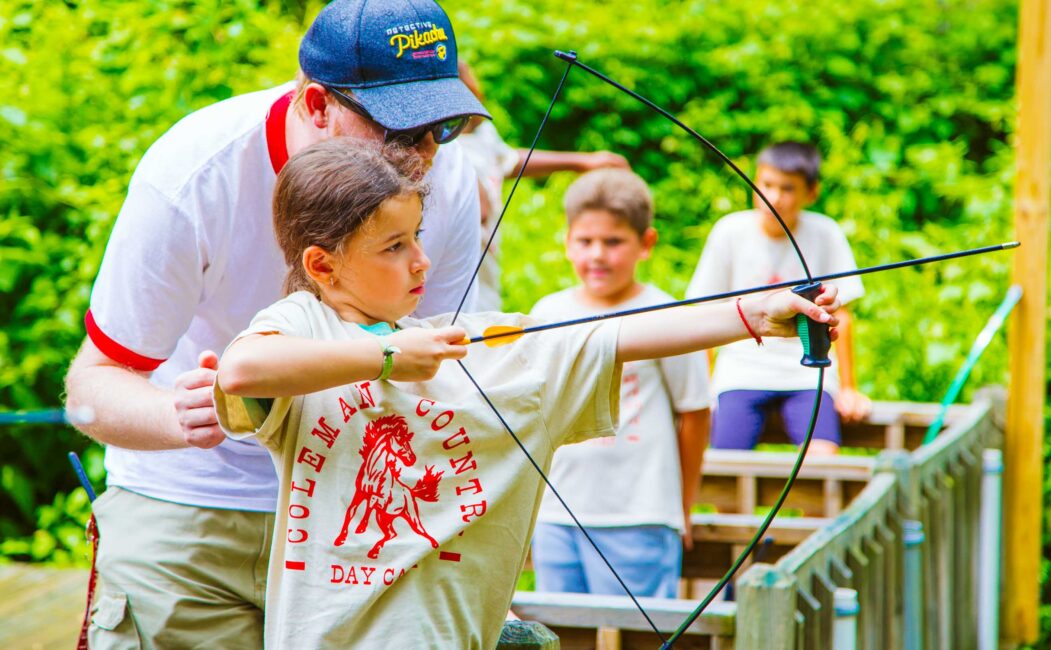 Instructor helps campers with archery