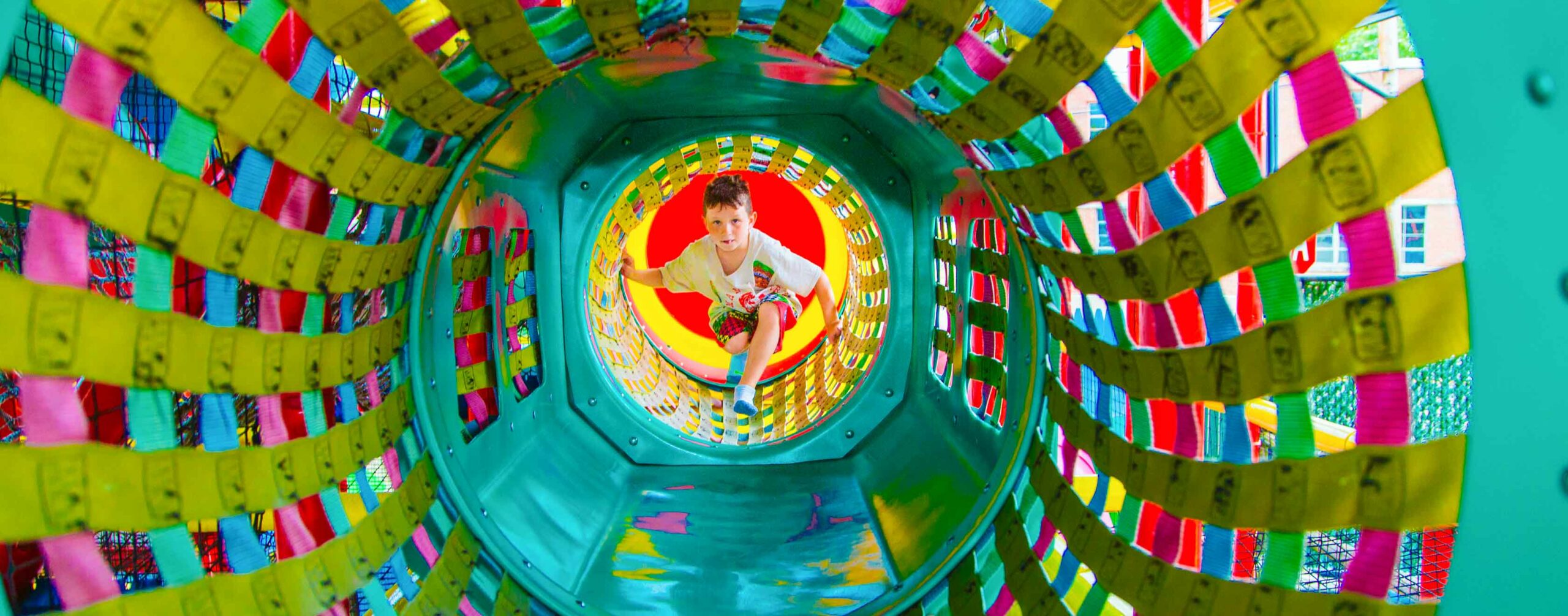 Boy climbs through colorful tunnel in play area