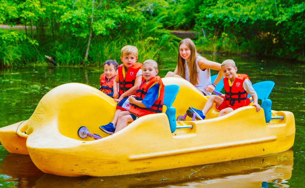 Group of young campers ride pedal boat