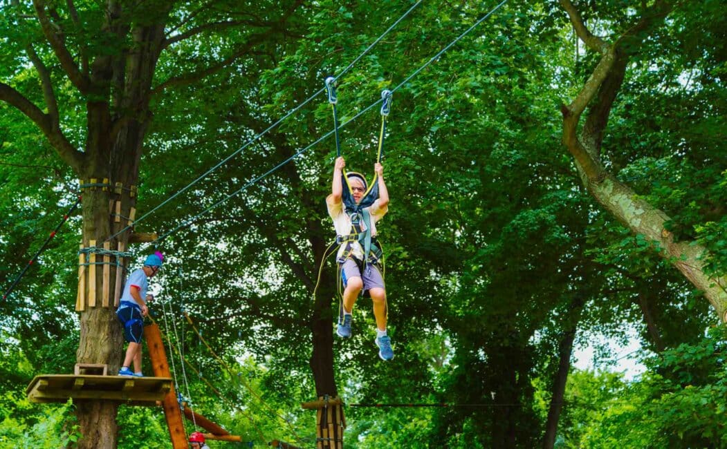 Camper ziplines through tree canopy