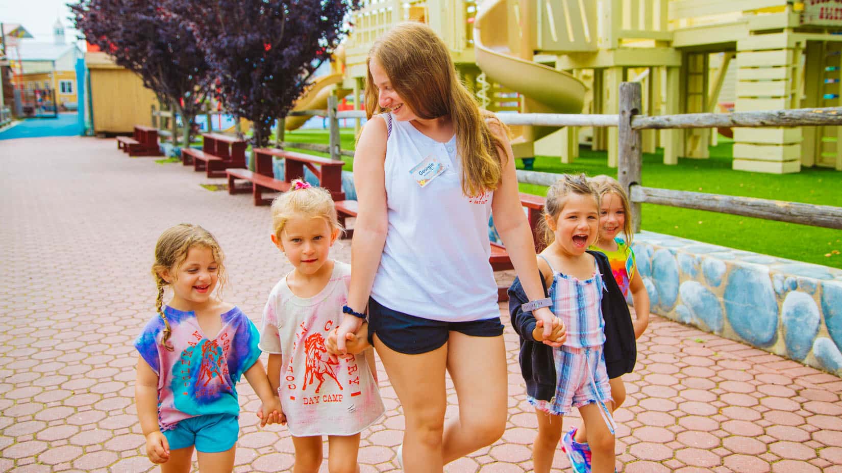 Counselor walks down path with group of young campers