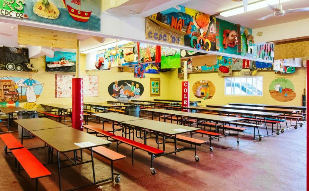 Interior of dining hall with picnic-style tables and art-covered walls