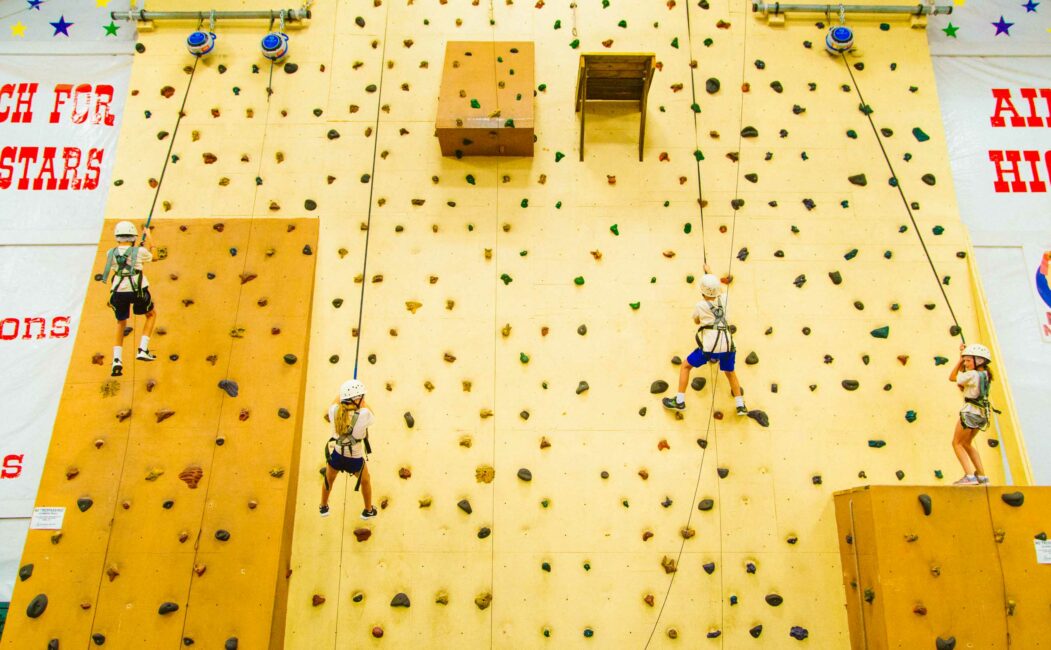 Campers climb indoor rock wall