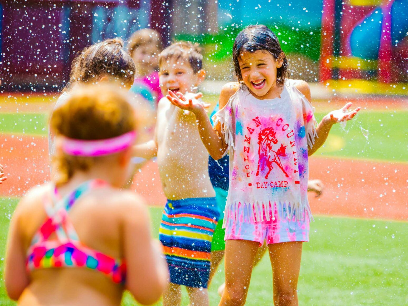 Smiling campers play in water spray